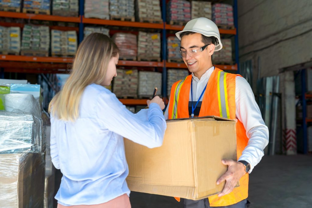 Female client of delivery service picks up the goods from the warehouse and signs the waybill